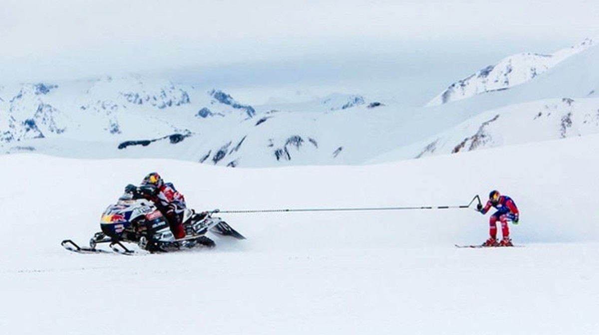 Ski racer gets towed by snowmobiler